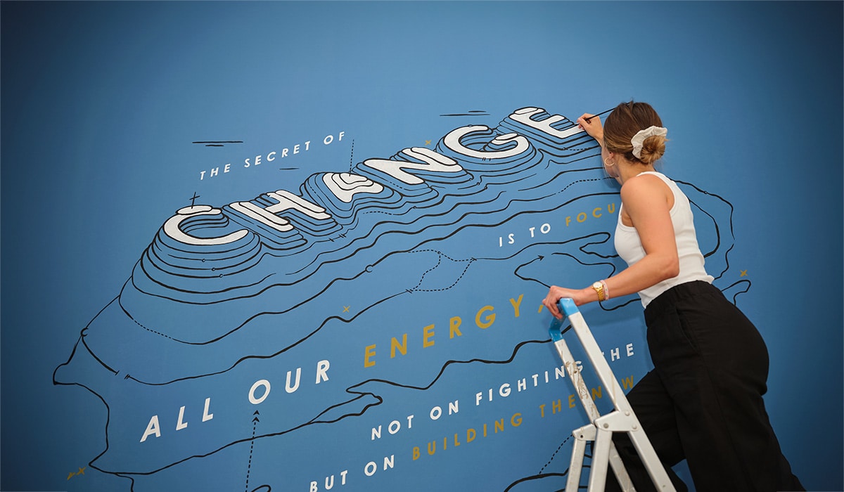 Frau bemalt blaue Wand mit Typografie, Illustration und Pinsel. Wandbemalung