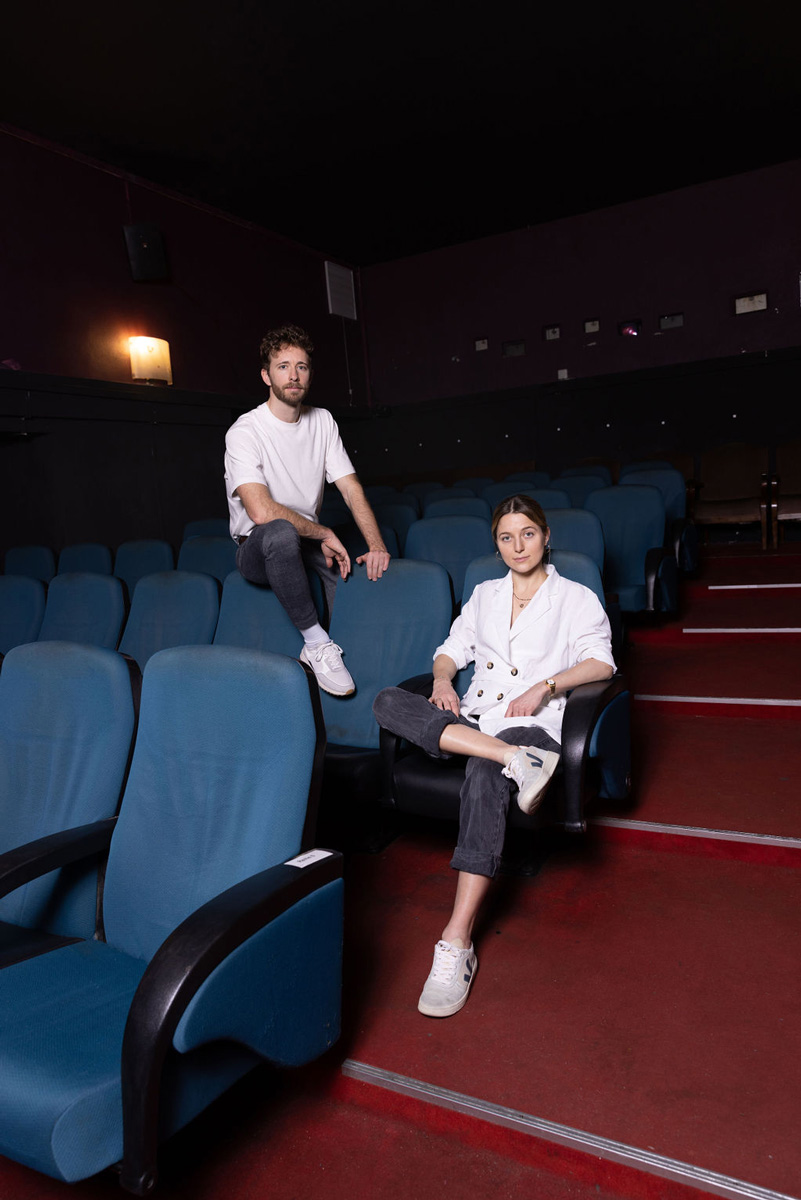 Das Desigduo, das Designteam von Bureau Zweima sitzt auf Stühlen im Kino Schikaneder