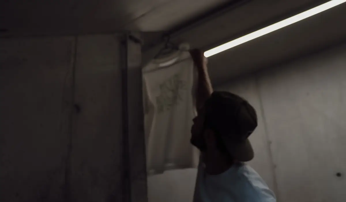Mann hängt Shirt auf in dunkler Umgebung