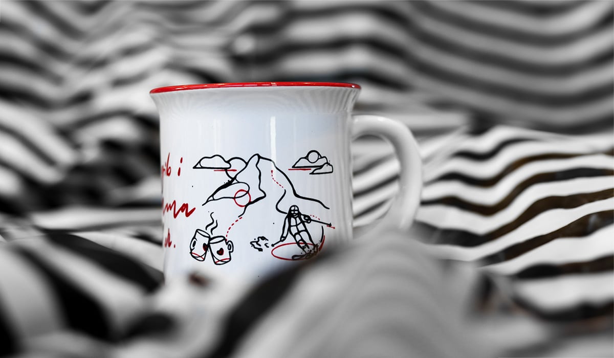 Tasse mit Illustrationen in Rot auf einem schwarz weiß gestreiftem Hintergrund
